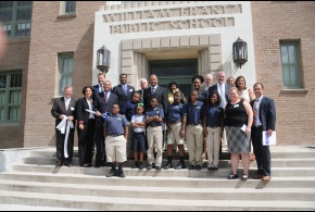 Officials from the Recovery School District and students and staff stand on the steps of Akili Academy to celebrate a ribbon cutting.