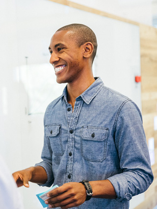 A man smiling as he stands near a whiteboard.