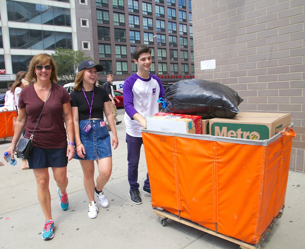 A mother and daughter walking with a Welcome Week leader who is helping them move in.