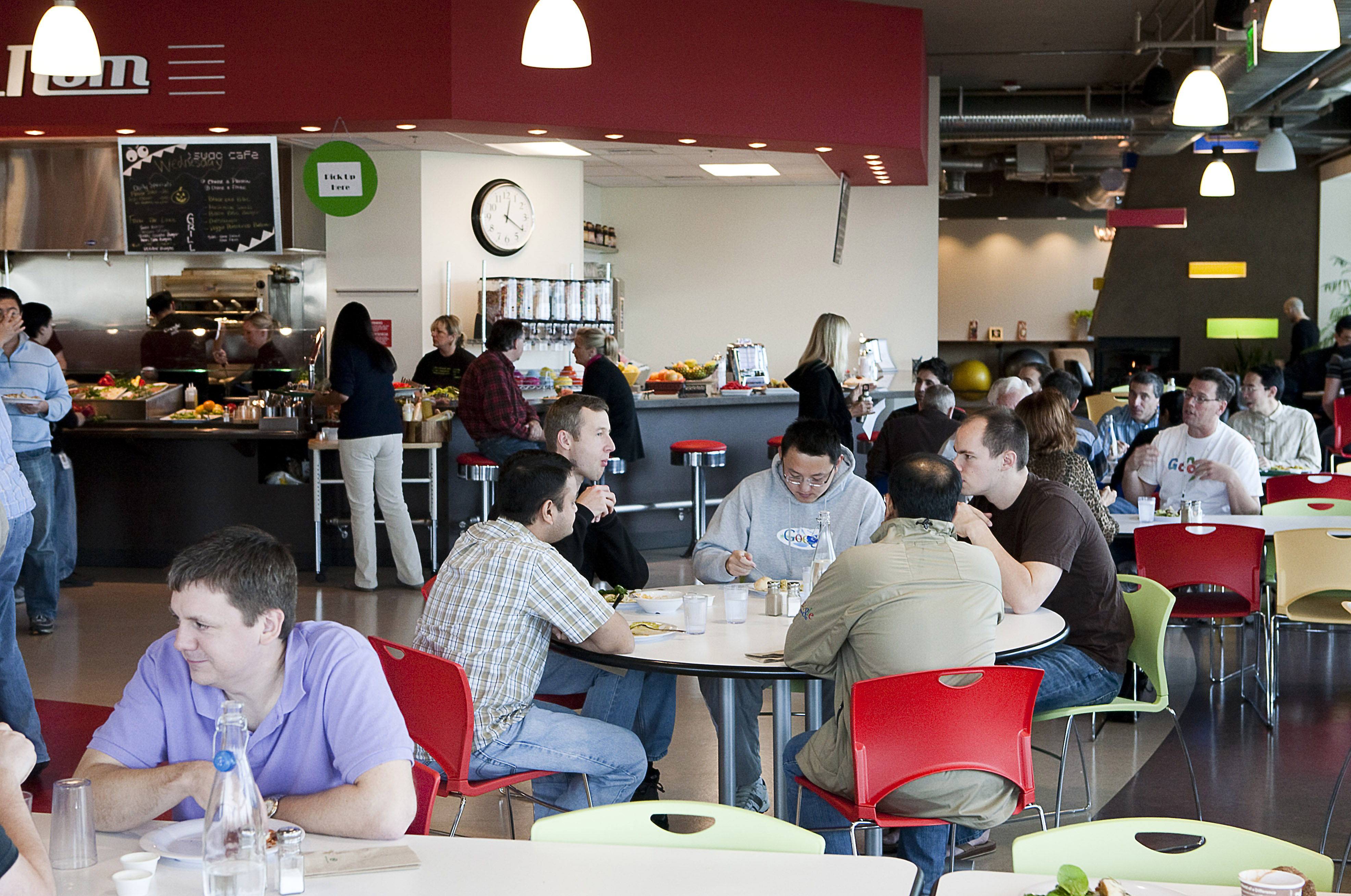 Google workers sitting in an office cafeteria.