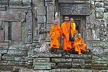 monks in orange robes on stone steps in Cambodia