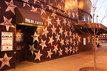 Silver stars on black painted exterior of First Avenue showing 7th St Entry door and awning