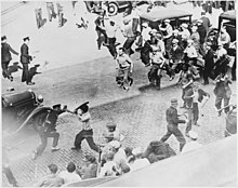 group of men holding pipes confronting police on street seen from above