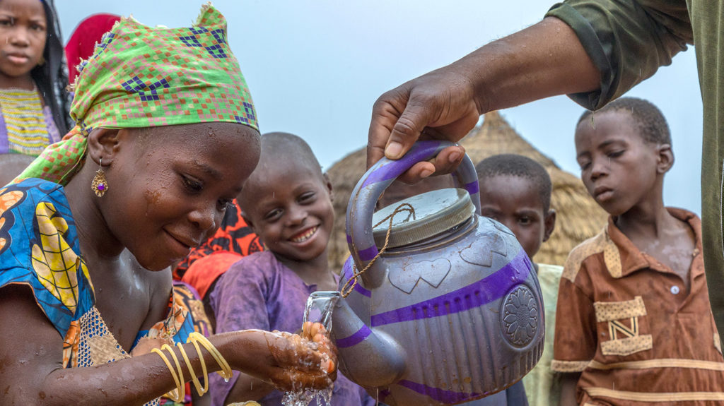 a group of children have water poured on their hands