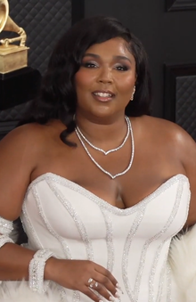 Lizzo smiles in a white dress