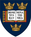 A shield displaying a coat of arms; on a dark blue background, an open book displays the words "Dominus illuminatio mea", with two gold crowns above and one below