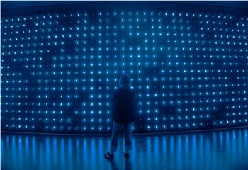 Person stands in front of a very large wall of blue light