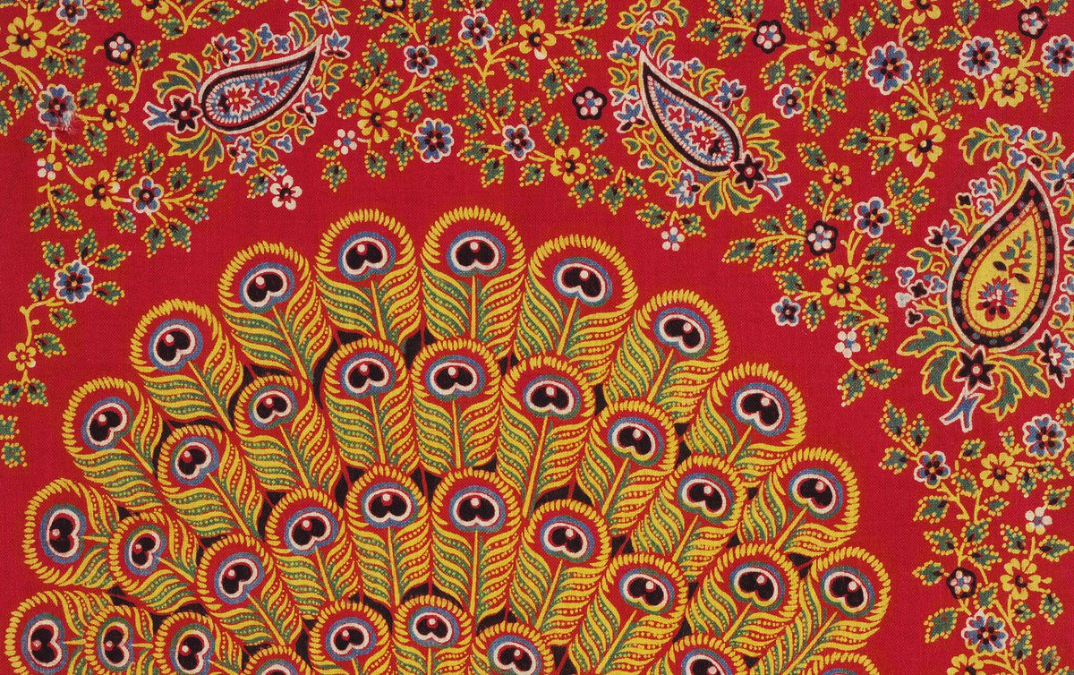 Photo of Turkey Red fabric. it's bright red with an exquisitely embroidered yellow and blue peacock on it, as well as flowers and the Paisley pattern.