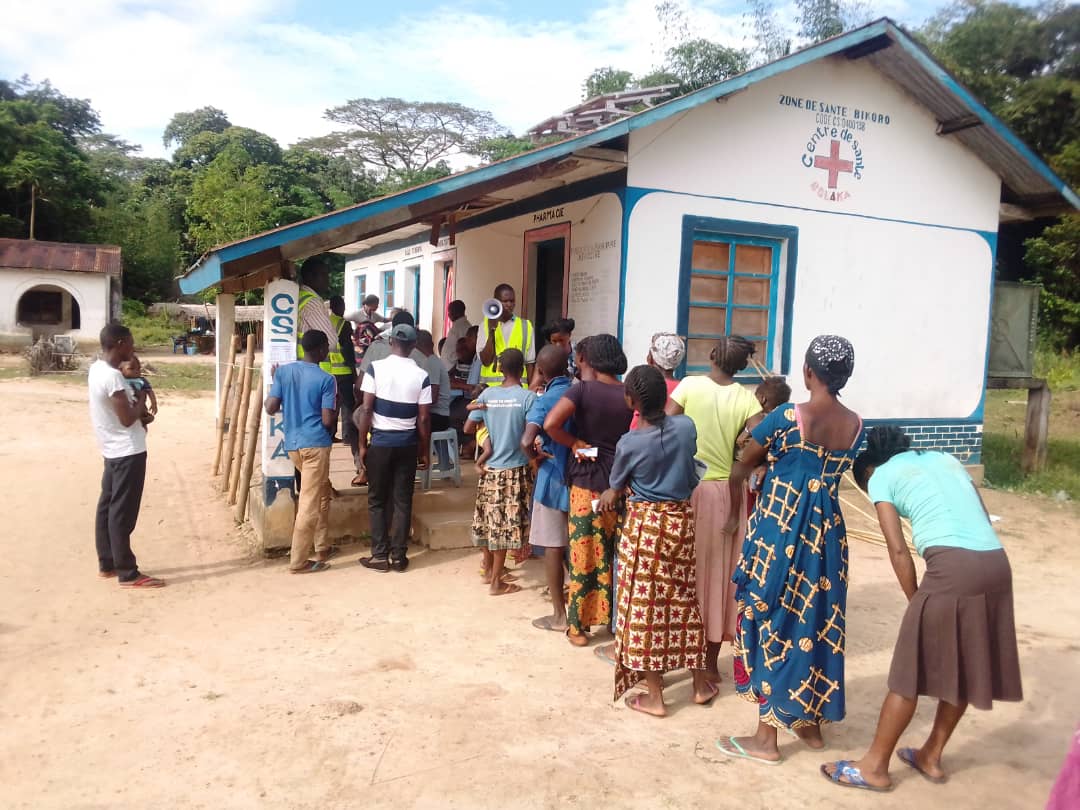 Community members queue outside the distribution point to receive their nets