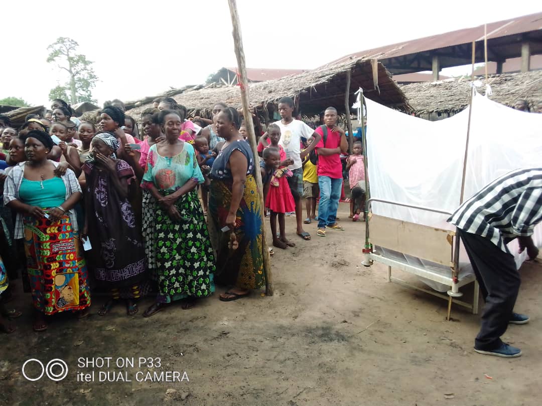 Community members wait to receive nets, next to an example of a hung net