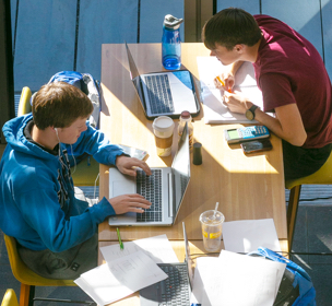 two male students sitting at a table and studying