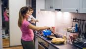 Parent holding baby while preparing food