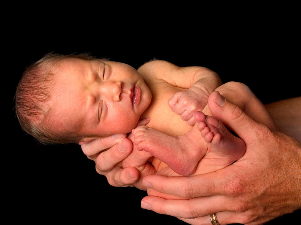 a newborn baby being held in an adult's hands