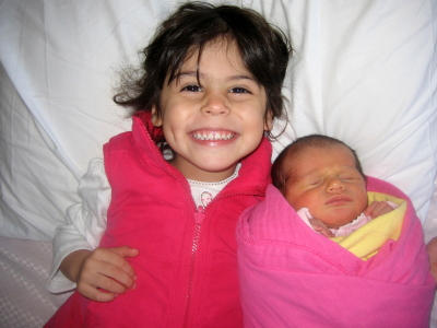 Proud little girl with her newborn baby sister