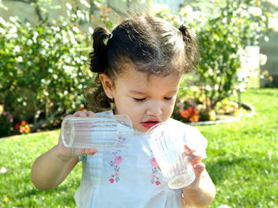 Toddler girl holding a couple of empty glasses