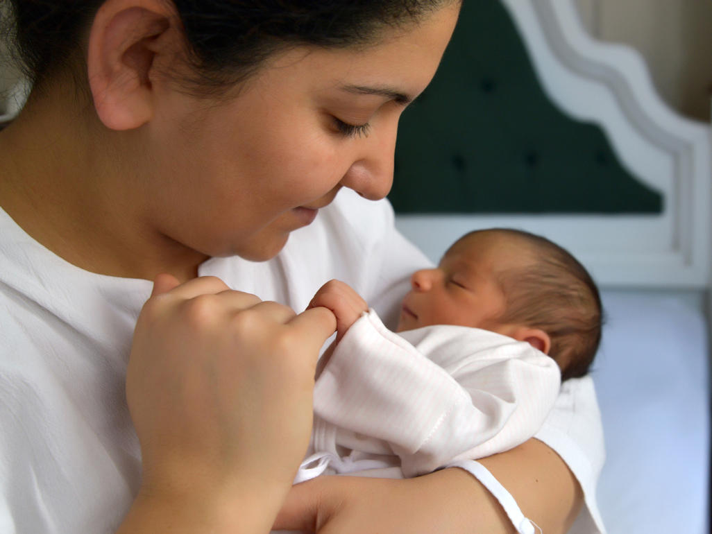 Sleeping baby holding her mum's finger