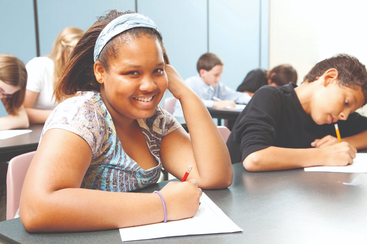 girl working at school desk and smiling at camera