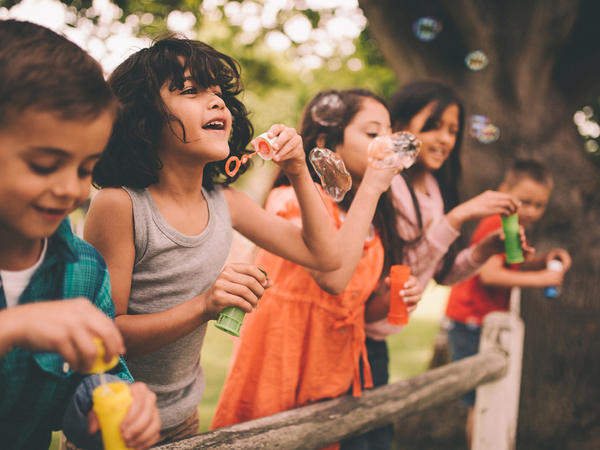 Group of happy preschooler blowing bubbles outdoors