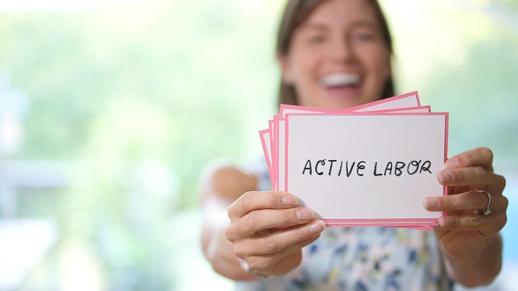 woman holding card with text: active labor