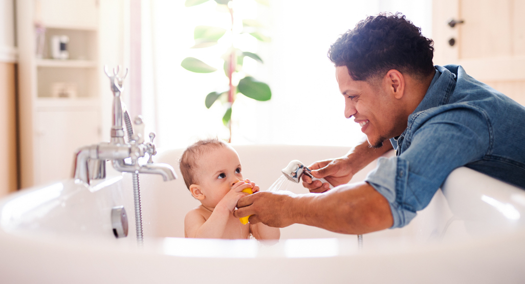 dad supervising young child in the bath tub