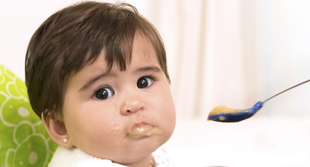 toddler being fed a meal with a spoon