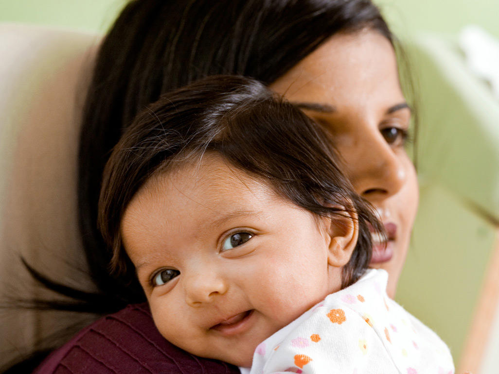 Baby smiling and resting against mum's shoulder