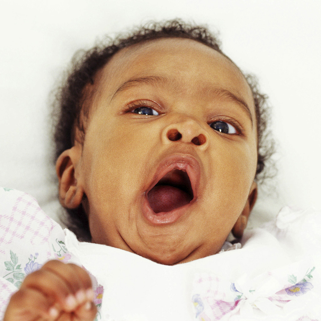 baby laying on it's back while yawning