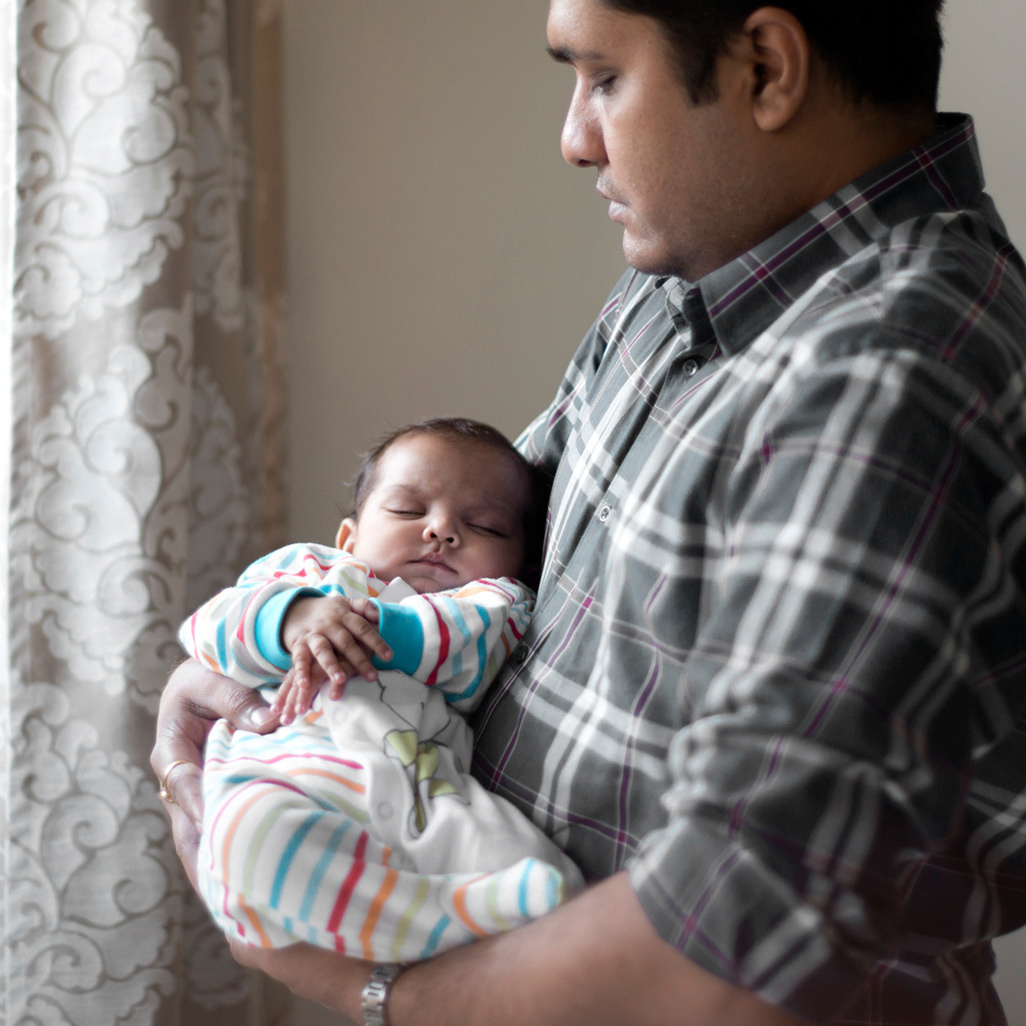 man cradling sleeping baby