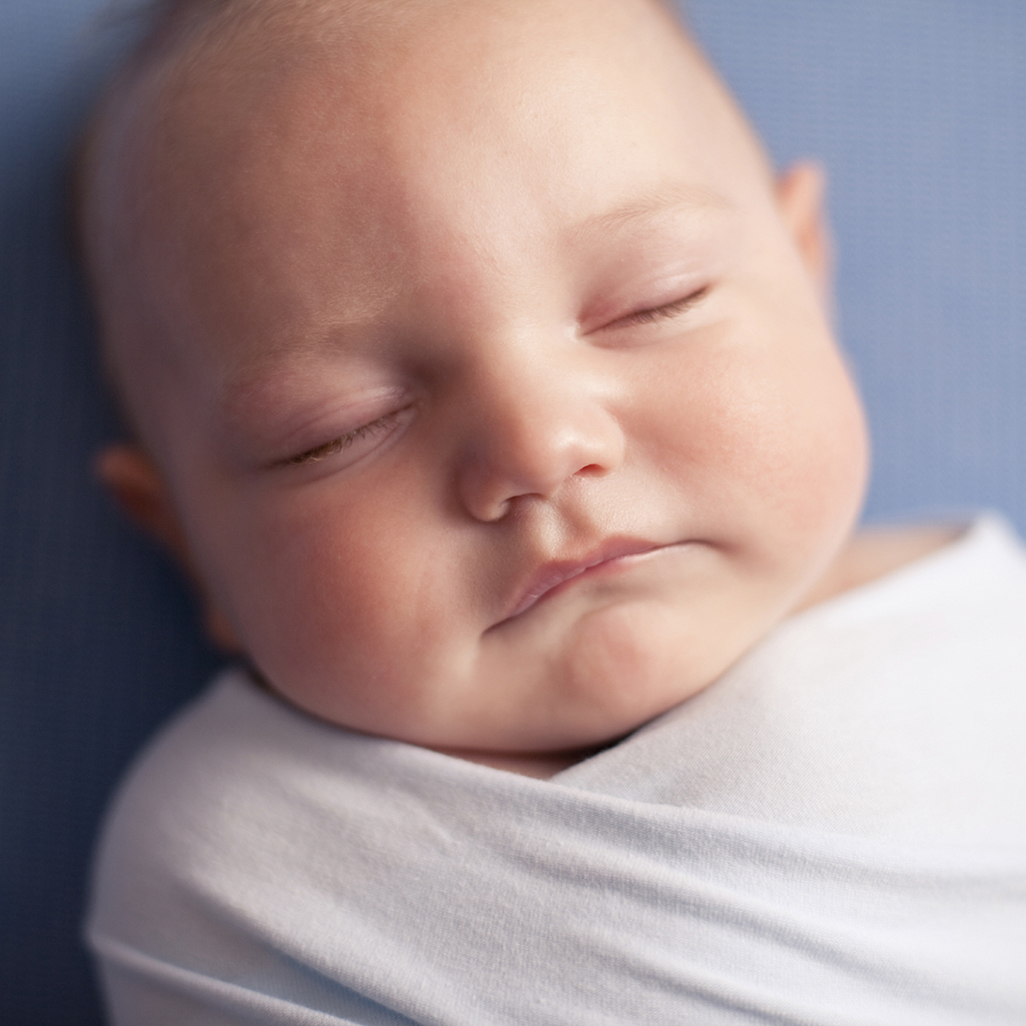 sleeping baby swaddled in white blanket