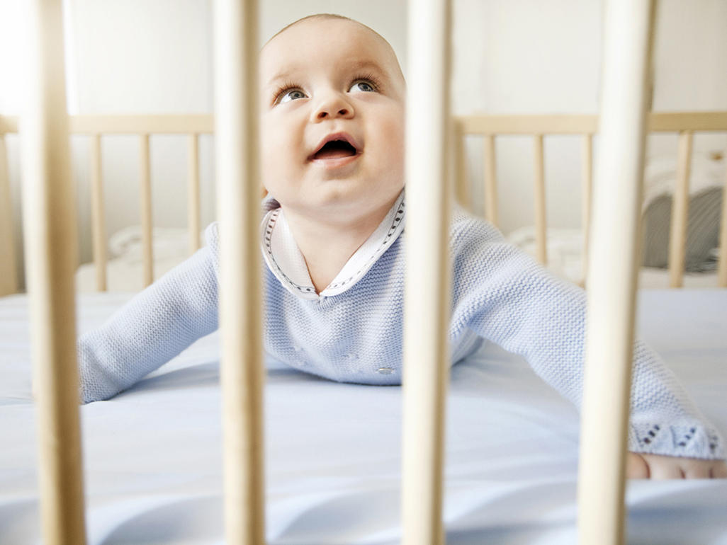 smiling baby lying in the crib and looking at something above