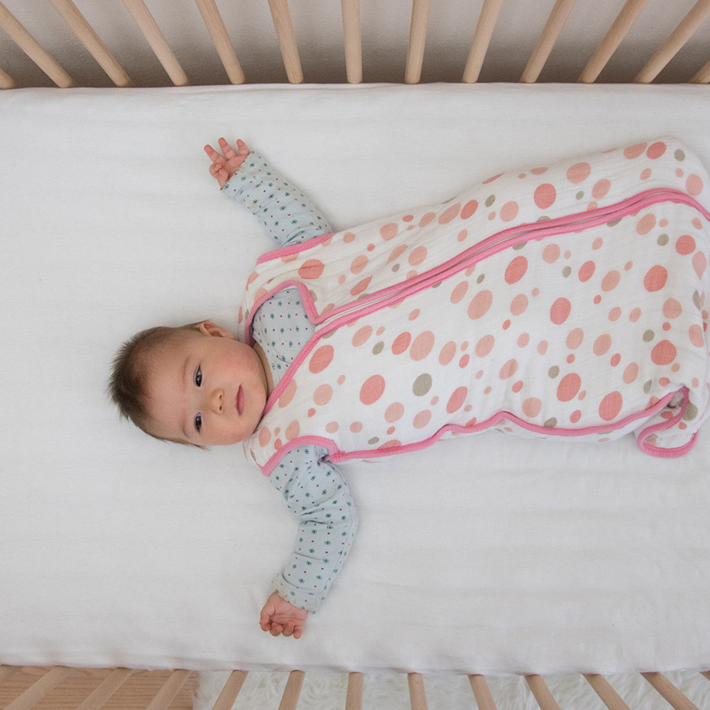 baby wearing sleep sack in crib