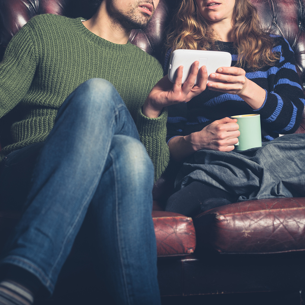 couple watching baby monitor while sitting on the couch