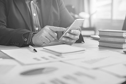 A person at a desk with papers and books holding a phone