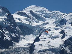 Panorama of Mont Blanc mountain range above gray clouds under a blue sky