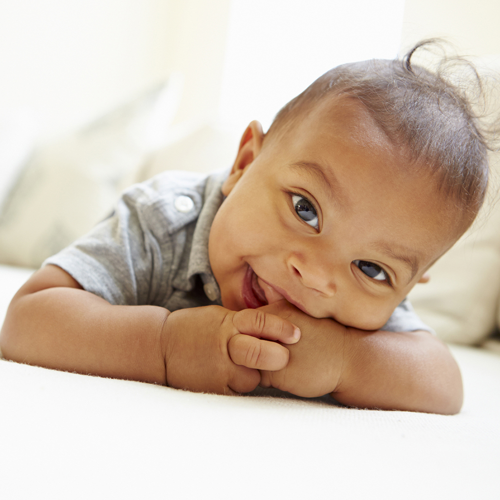 baby lying on his stomach with a finger in his mouth