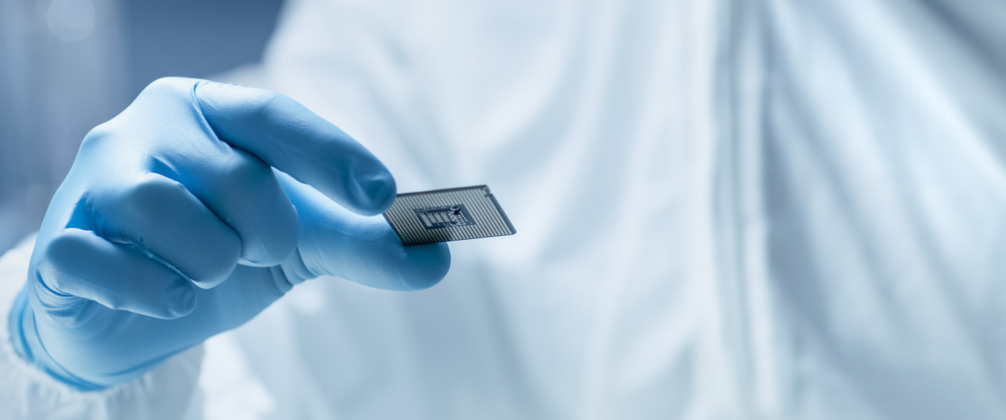 Person wearing blue latex gloves holds a silver-coloured grey chip 