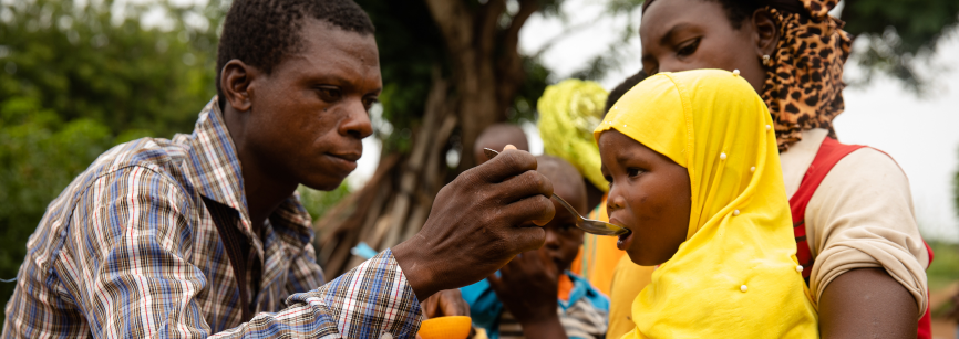 Man feeding a child which a woman is holding