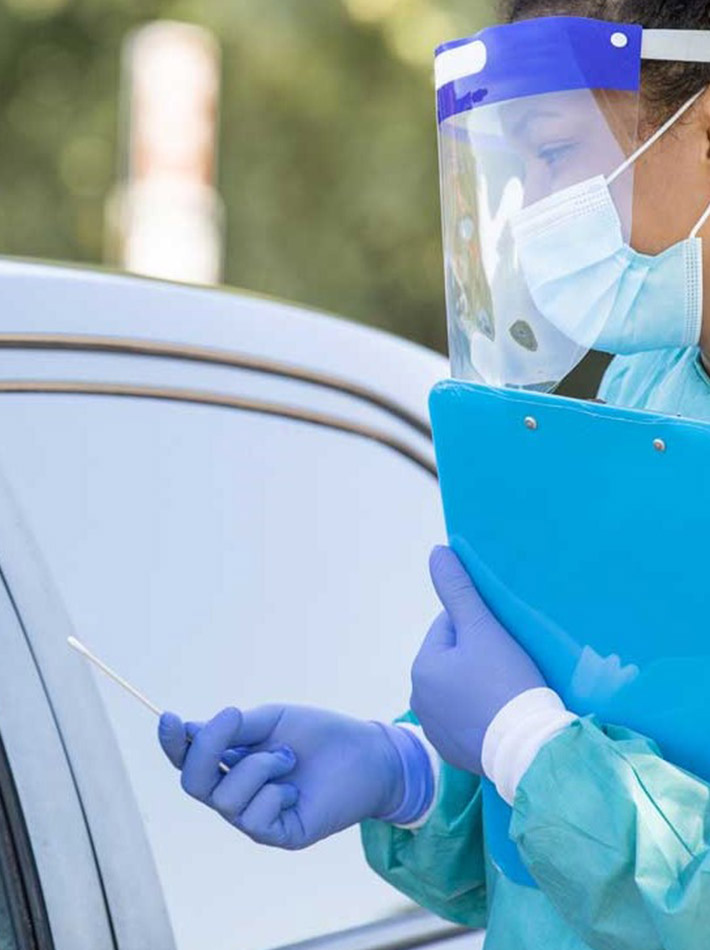 Un trabajador de la salud con cubreboca ayuda a un paciente durante una prueba de COVID-19.