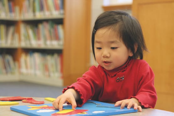 Little girl in red shirt doing a puzzle