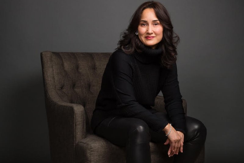 Cynthia Breazeal is dressed in black and sitting in an armchair.