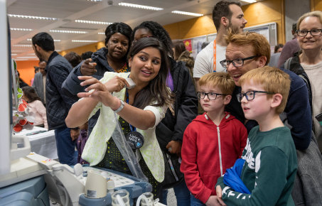 A family listen watch an Imperial reseacher undertake a demonstration at Imperial Festival