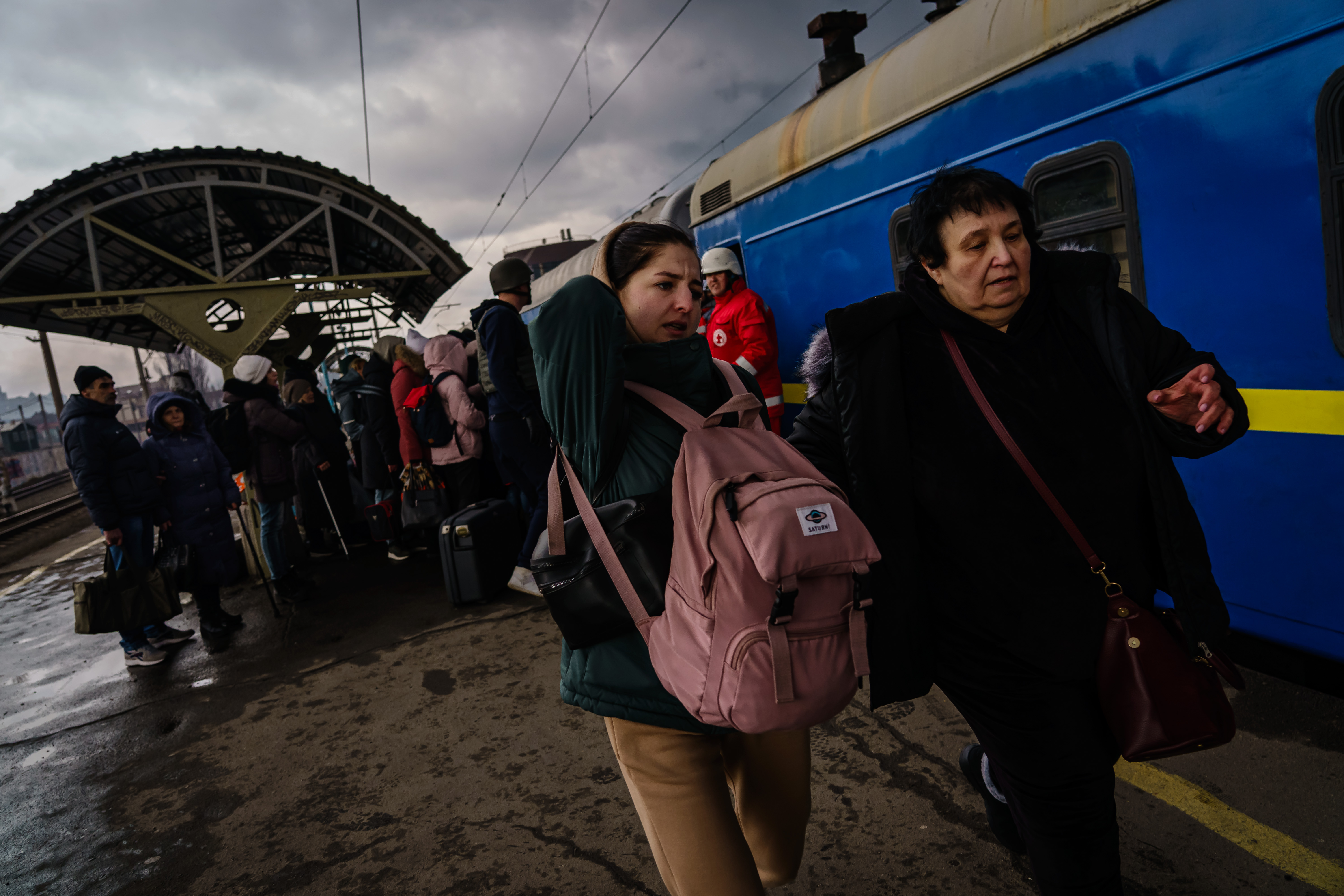 People next to a train carrying bags.