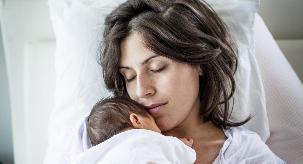 Mother holding a newborn baby to her chest.