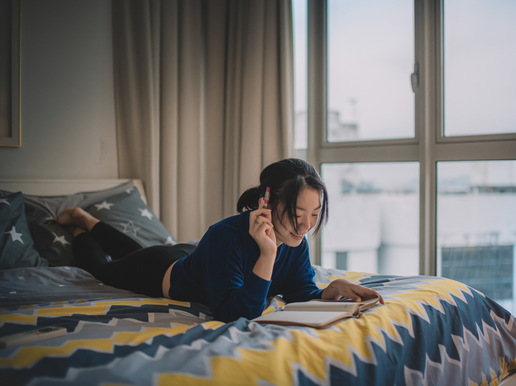 smiling woman on bed making notes