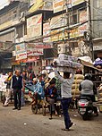 Vendors and signs along a busy dirt street in Old Delhi