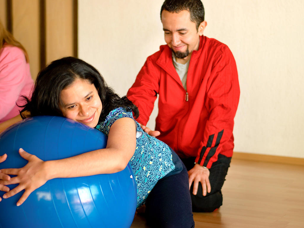 Schwangere umfasst einen Pezziball, der Partner massiert ihren Rücken