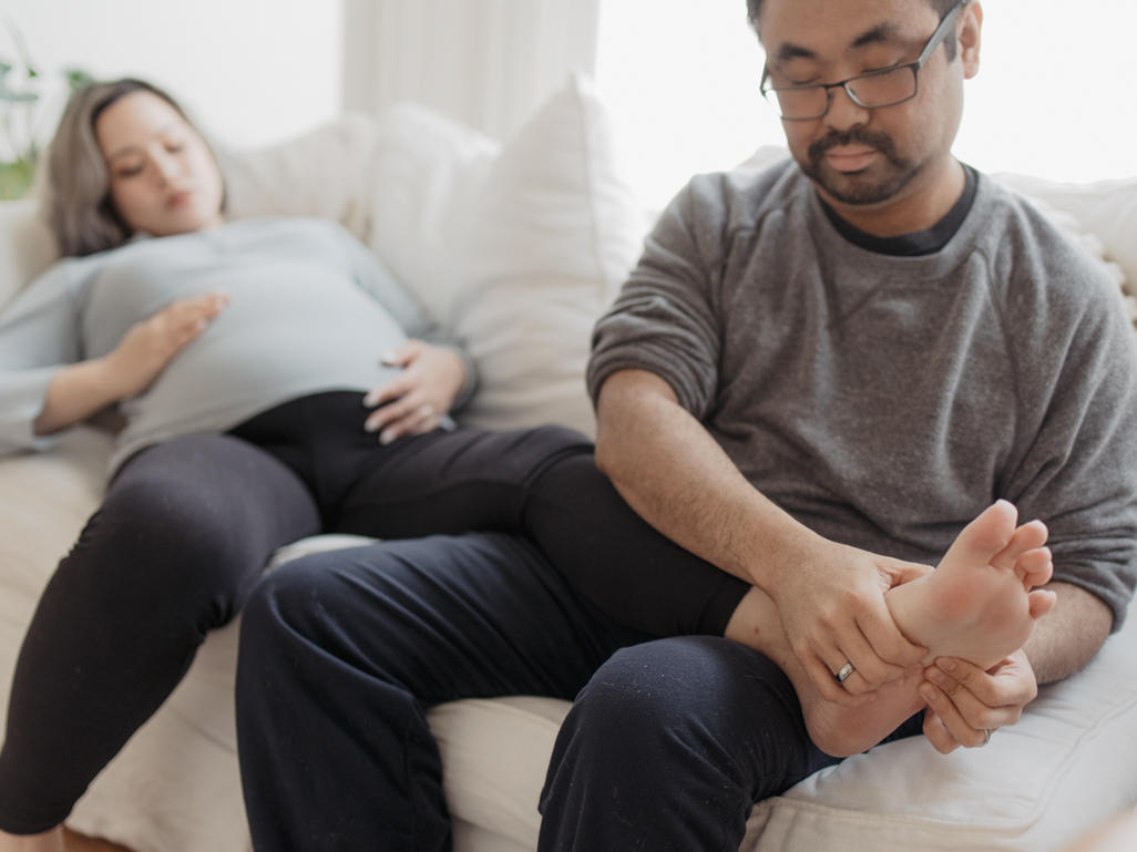 pregnant woman with swollen feet and ankles getting a foot massage from her partner