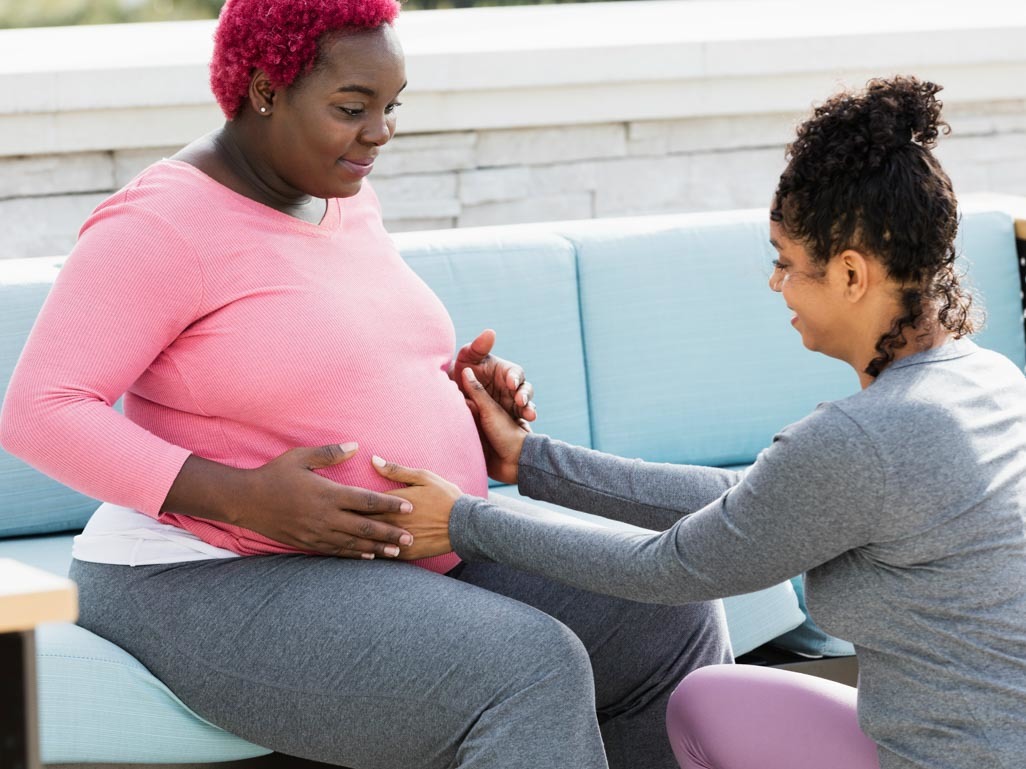 A Black doula speaking with a Black pregnant woman.