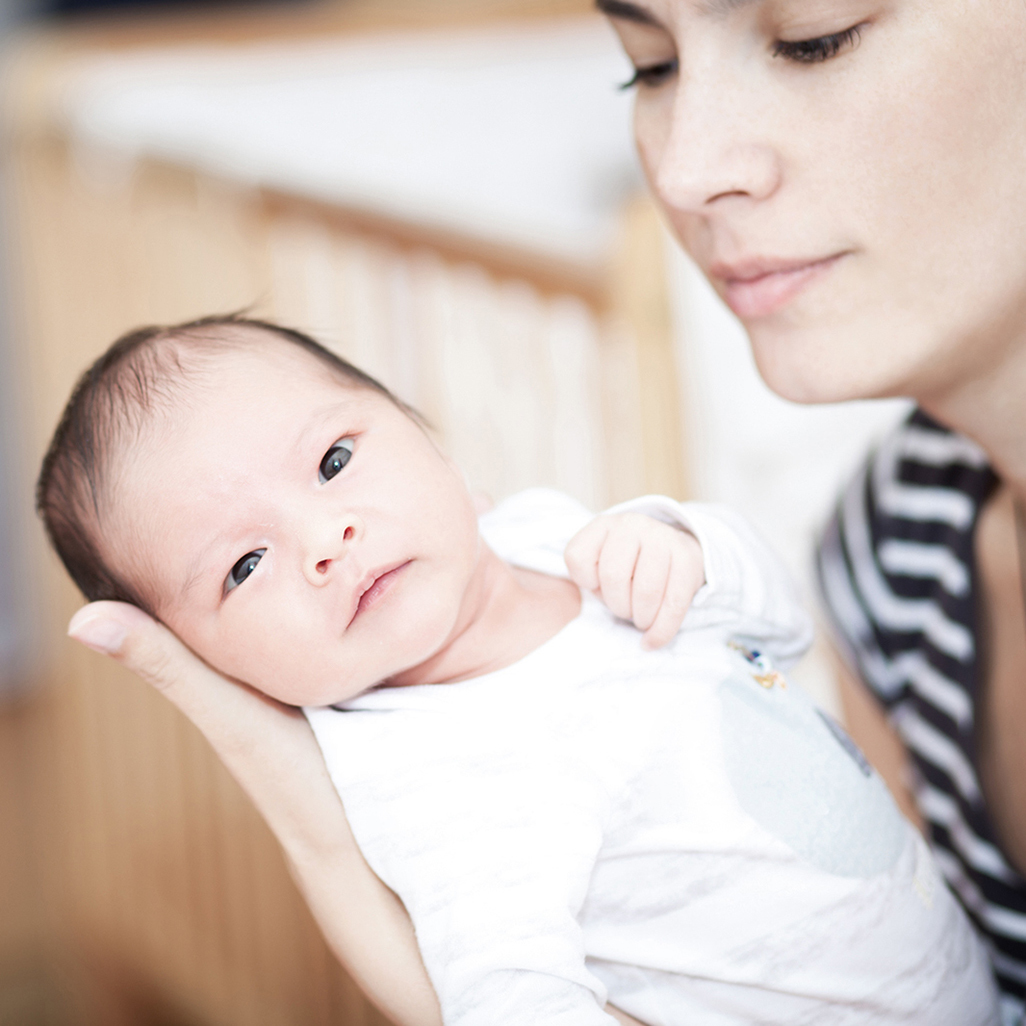 woman holding her newborn in one arm