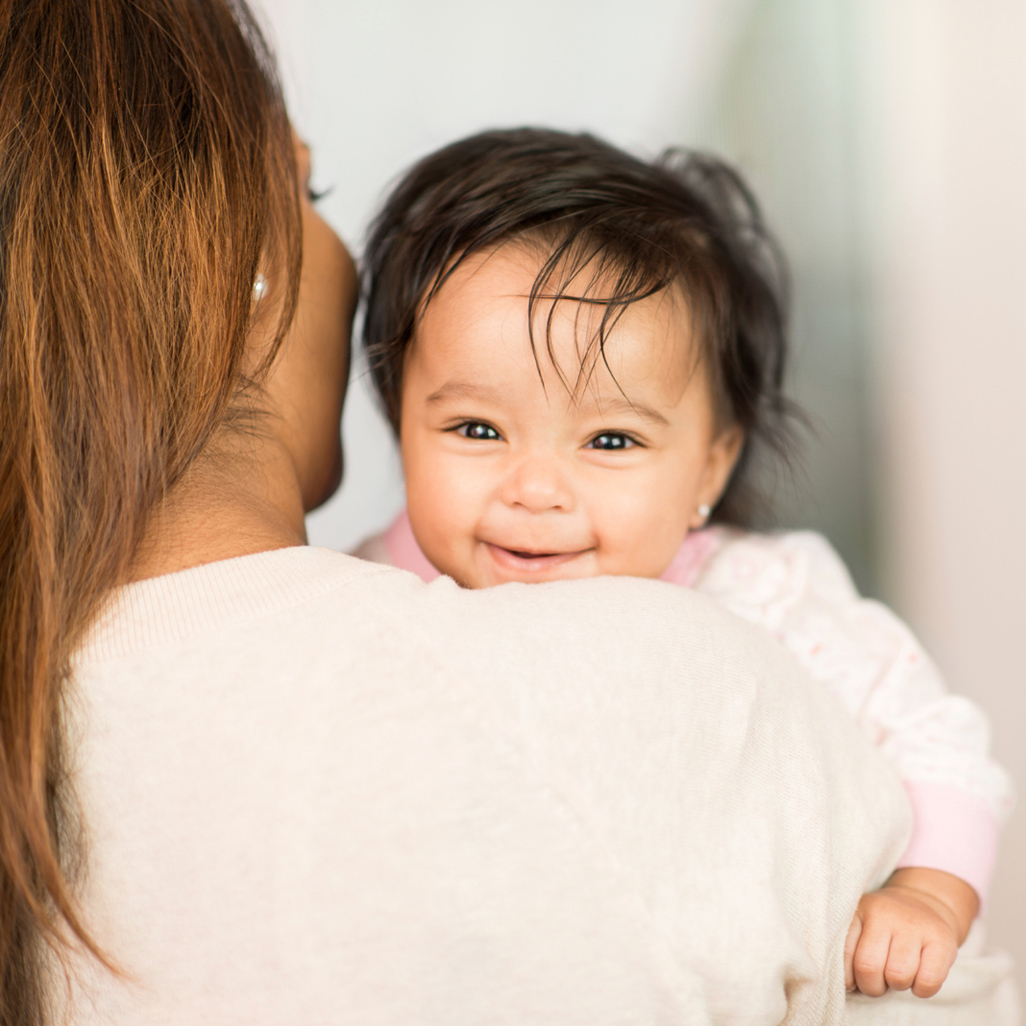 mom holding smiling baby on shoulder